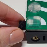 fingers pulling the MicroSD card out of the edge of the AudioMoth near the large square bump dot